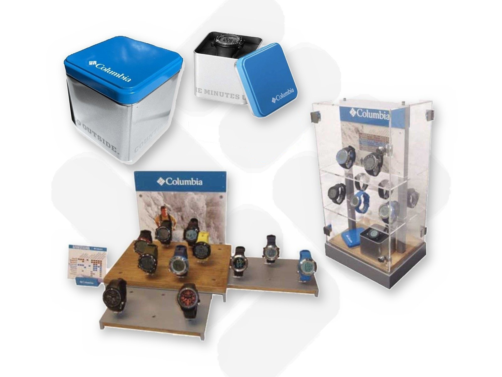 Columbia watch packaging, the blue-lidded silver tin and the open tin with a black digital watch, above a wood and steel counter display and a clear acrylic display case